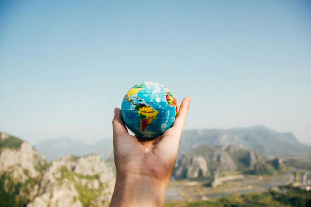 Foto di Porapak Apichodilok: https://www.pexels.com/it-it/foto/persona-che-tiene-il-globo-del-mondo-di-fronte-alla-montagna-346885/